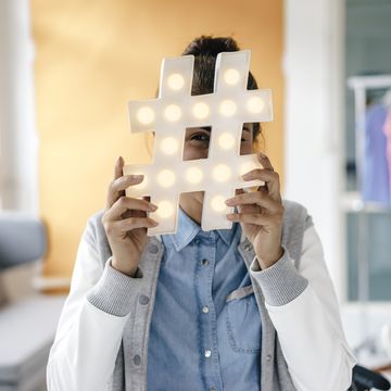 Young woman hiding behind hashtag sign in studio young woman hiding behind hashtag sign in studio